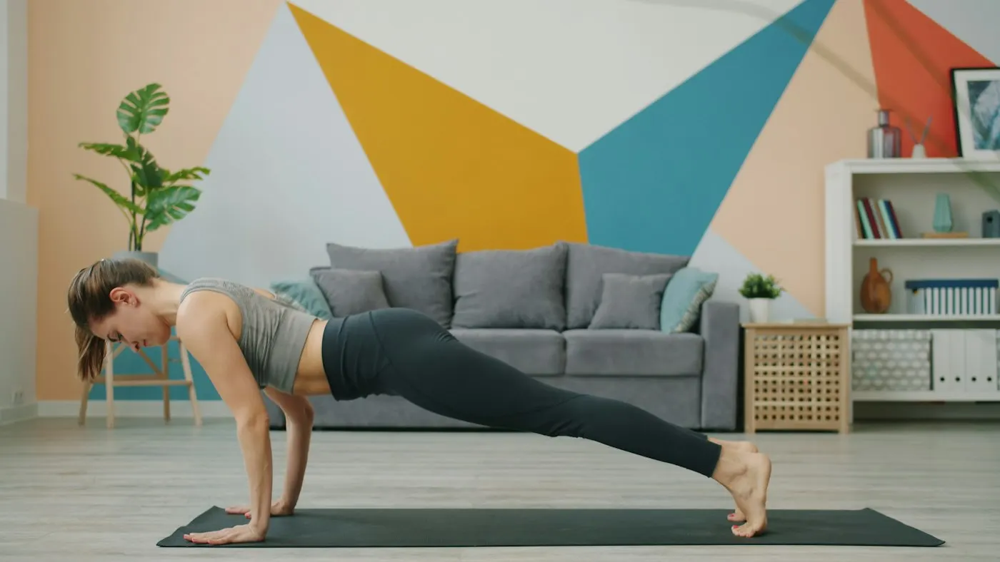 Woman holding a high plank on an exercise mat in a bright living room
